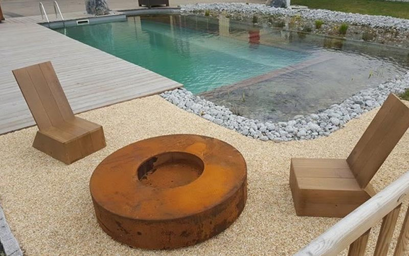 Une image présentant le brasero rond en acier corten positionné près d'une piscine, offrant une ambiance relaxante et élégante.